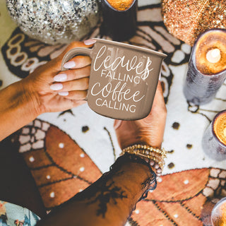fall coffee station with brown quote mug
neutral brown fall mug next to plaid blanket
leaves falling coffee calling mug with cinnamon sticks
autumn morning coffee cup by window with falling leaves
brown ceramic fall mug on farmhouse kitchen island
