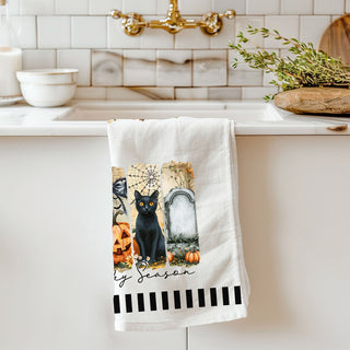 neutral halloween kitchen towel with modern spooky illustrations
ghost pumpkin spiderweb towel hanging on oven handle
stylish halloween tea towel with black cat grave and pumpkins
spooky season bar cart towel with ghost and jack o lantern